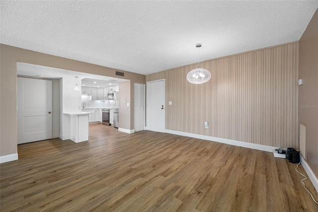 10216 Regal Dr Unit 208, Largo, FL 33774 - unfurnished living room with wood finished floors, a textured ceiling, baseboards, a chandelier, and a sink