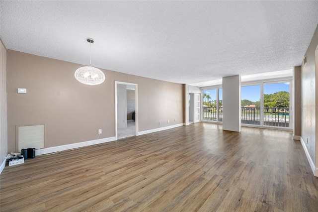 10216 Regal Dr Unit 208, Largo, FL 33774 - unfurnished living room featuring wood finished floors, a chandelier, a textured ceiling, and baseboards