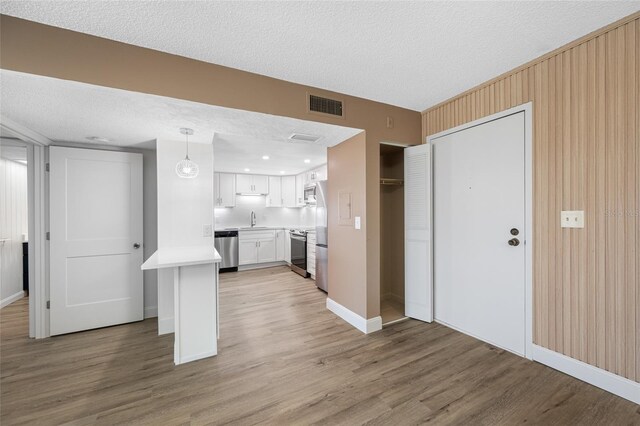 10216 Regal Dr Unit 208, Largo, FL 33774 - kitchen with appliances with stainless steel finishes, a textured ceiling, white cabinets, light countertops, and light wood-type flooring