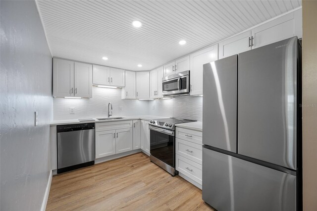 10216 Regal Dr Unit 208, Largo, FL 33774 - kitchen featuring appliances with stainless steel finishes, a sink, light countertops, backsplash, and light wood finished floors