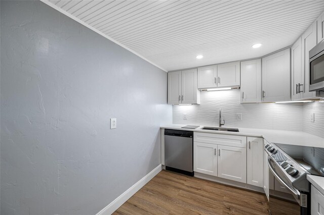 10216 Regal Dr Unit 208, Largo, FL 33774 - kitchen featuring appliances with stainless steel finishes, a sink, decorative backsplash, baseboards, and wood finished floors