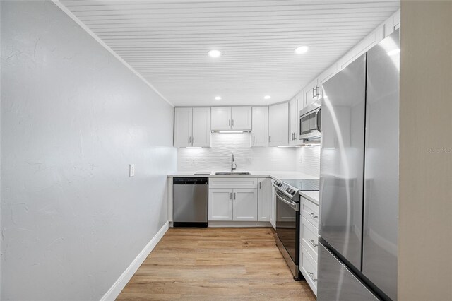 10216 Regal Dr Unit 208, Largo, FL 33774 - kitchen with appliances with stainless steel finishes, a sink, light wood-type flooring, white cabinetry, and tasteful backsplash