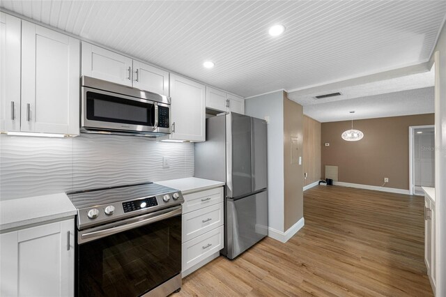 10216 Regal Dr Unit 208, Largo, FL 33774 - kitchen featuring appliances with stainless steel finishes, baseboards, light countertops, light wood-type flooring, and white cabinets