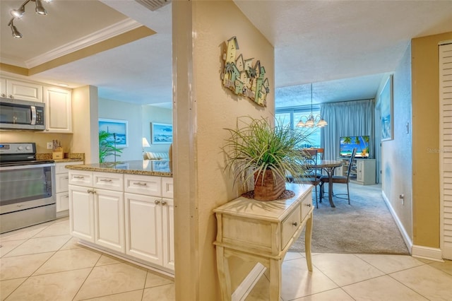 14146 Gulf Blvd Unit 4B, Madeira Beach, FL 33708 - kitchen with stainless steel appliances, white cabinetry, a chandelier, light tile patterned floors, and crown molding