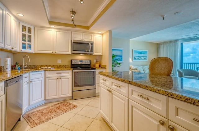 14146 Gulf Blvd Unit 4B, Madeira Beach, FL 33708 - kitchen with appliances with stainless steel finishes, light tile patterned floors, light stone counters, white cabinetry, and glass insert cabinets