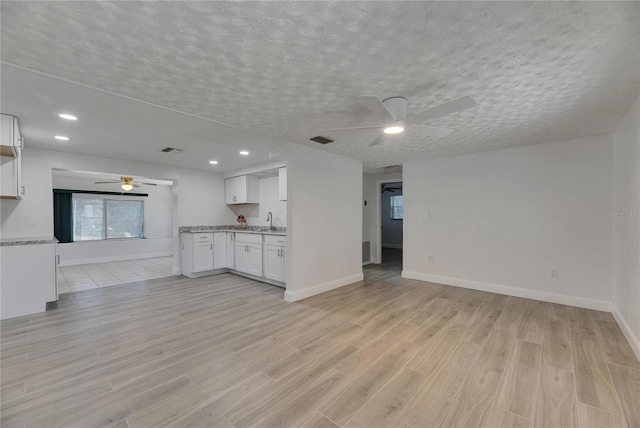 825 Seabreeze Dr, Ruskin, FL 33570 - unfurnished living room with ceiling fan, light wood finished floors, baseboards, a textured ceiling, and a sink