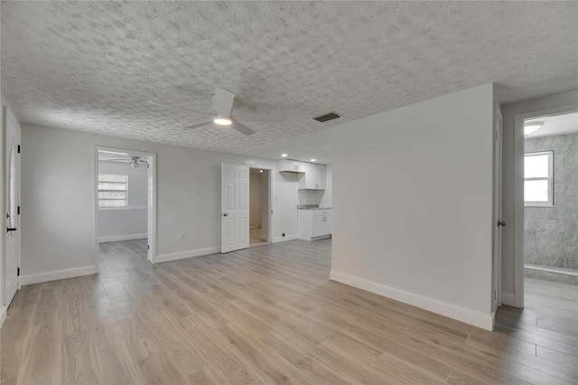 825 Seabreeze Dr, Ruskin, FL 33570 - unfurnished living room with ceiling fan, plenty of natural light, light wood finished floors, a textured ceiling, and baseboards