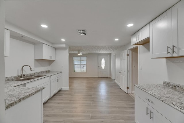 825 Seabreeze Dr, Ruskin, FL 33570 - kitchen featuring a sink, white cabinetry, recessed lighting, light wood-style floors, and light stone countertops