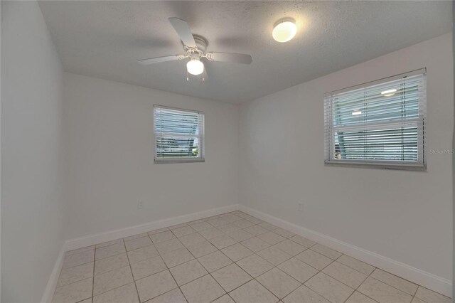 825 Seabreeze Dr, Ruskin, FL 33570 - empty room with baseboards, a ceiling fan, light tile patterned floors, and a textured ceiling