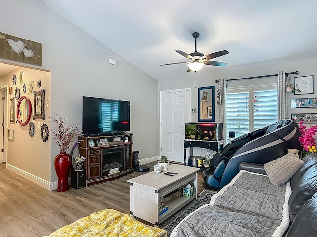 living room featuring light wood finished floors, ceiling fan, baseboards, and lofted ceiling