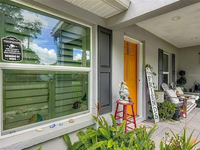 view of exterior entry with stucco siding and covered porch