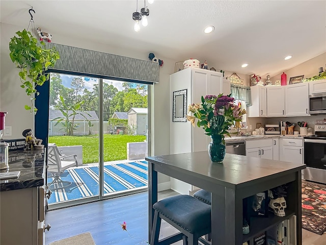 kitchen featuring appliances with stainless steel finishes, white cabinetry, wood finished floors, open shelves, and a sink