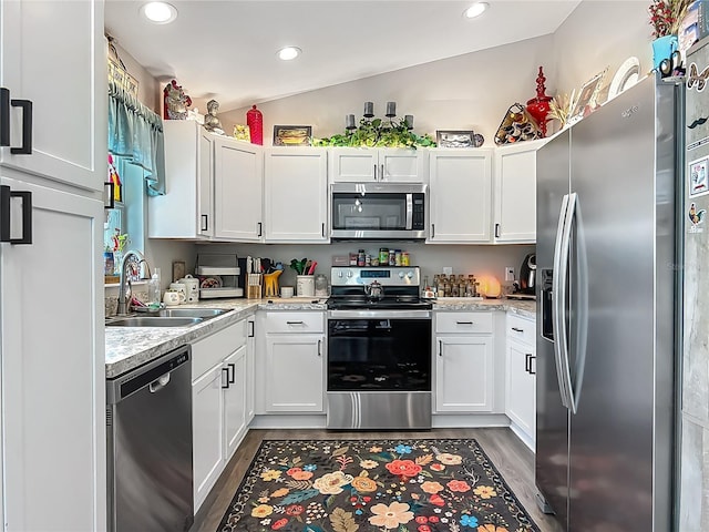 kitchen featuring stainless steel appliances, a sink, wood finished floors, light countertops, and white cabinetry