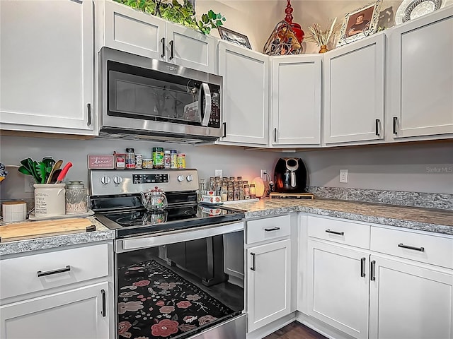 kitchen with stainless steel appliances, light countertops, white cabinetry, and dark wood-style floors