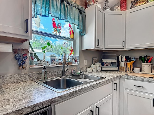 kitchen featuring a sink, light countertops, white cabinets, and dishwasher