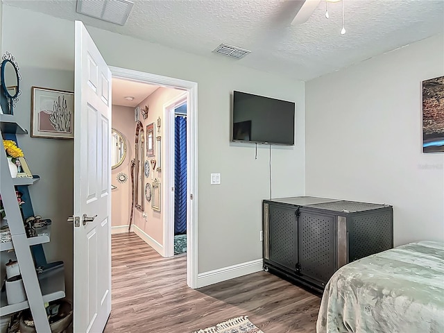 bedroom featuring wood finished floors, a textured ceiling, and baseboards