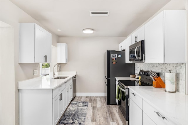 1530 Picardy Cir, Clearwater, FL 33755 - kitchen featuring stainless steel appliances, light wood finished floors, white cabinets, and light countertops