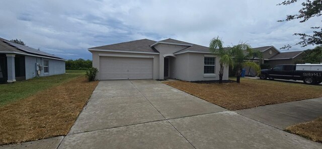 ranch-style house featuring driveway, a garage, stucco siding, a front yard, and a shingled roof