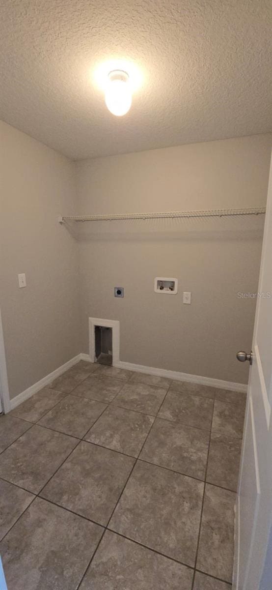 clothes washing area featuring a textured ceiling, electric dryer hookup, washer hookup, tile patterned flooring, and a fireplace