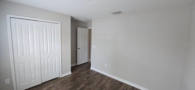 unfurnished bedroom featuring baseboards, dark wood-style floors, and a closet