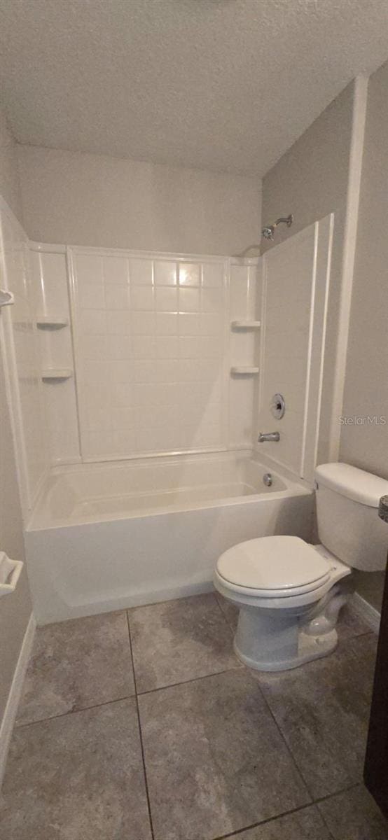 full bathroom featuring toilet, a textured ceiling, washtub / shower combination, tile patterned flooring, and baseboards