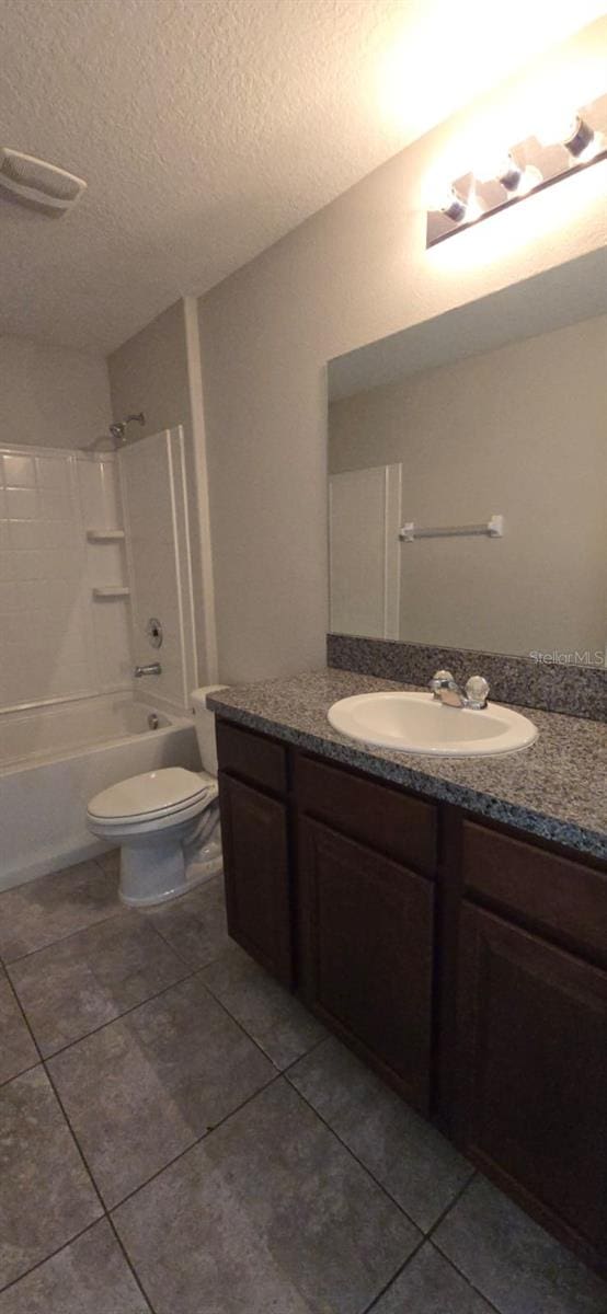 bathroom with tile patterned floors, vanity,  shower combination, toilet, and a textured ceiling