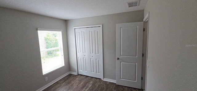 unfurnished bedroom with dark wood finished floors, a closet, and baseboards