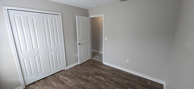 unfurnished bedroom featuring dark wood-style floors, a closet, and baseboards