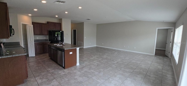 kitchen featuring black appliances, lofted ceiling, a center island with sink, light tile patterned flooring, and a sink