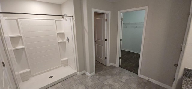 full bathroom with a shower stall, baseboards, tile patterned floors, and a walk in closet