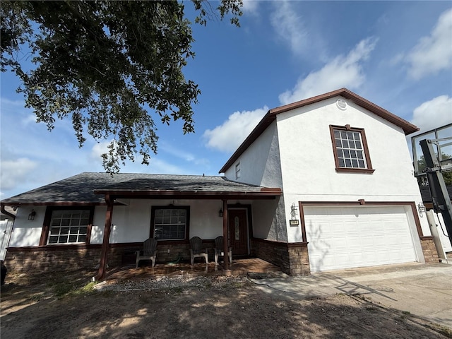 view of front of house with stone siding, covered porch, stucco siding, and an attached garage