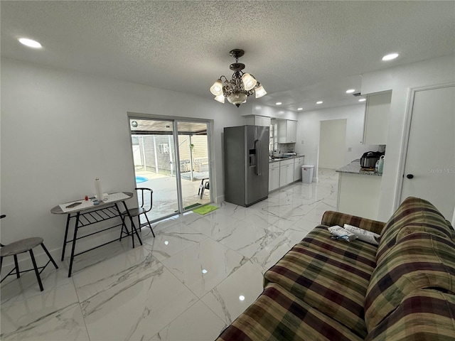 living room with a chandelier, light marble finish flooring, a textured ceiling, and recessed lighting