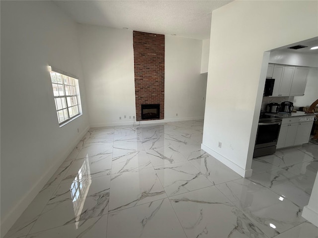 unfurnished living room featuring baseboards, light marble finish floors, a brick fireplace, and a textured ceiling