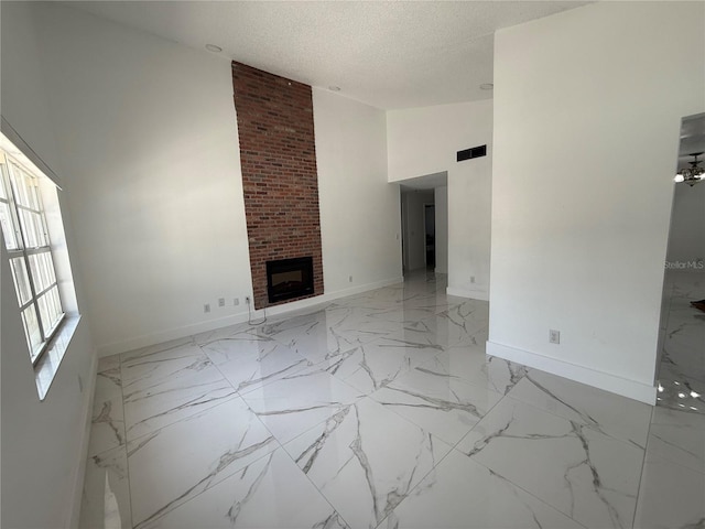 unfurnished living room featuring baseboards, a fireplace, a textured ceiling, light marble finish flooring, and high vaulted ceiling