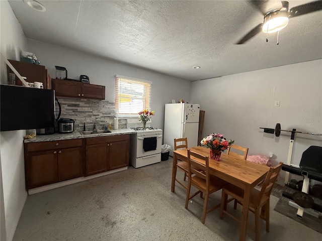 kitchen featuring white appliances, a sink, a textured ceiling, light countertops, and a ceiling fan