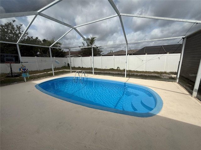 view of swimming pool featuring a fenced backyard, a patio, and glass enclosure