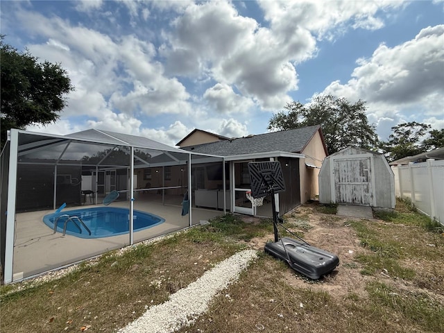 view of swimming pool featuring a shed, a patio area, an outdoor structure, fence, and a lanai
