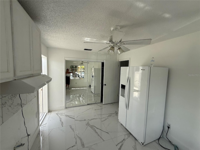 kitchen with white fridge with ice dispenser, ceiling fan, a textured ceiling, and light marble finish floors