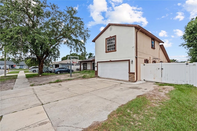 3104 Apricot St, Seffner, FL 33584 - view of side of property with a gate, a garage, concrete driveway, stone siding, and stucco siding