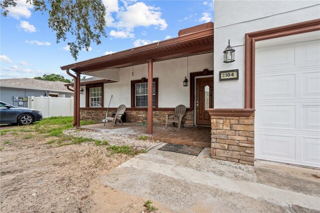 3104 Apricot St, Seffner, FL 33584 - view of exterior entry featuring covered porch, stone siding, stucco siding, and a garage