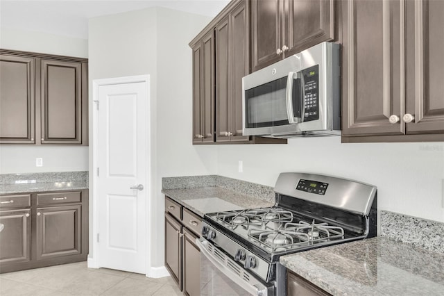 1028 Oliveto Verdi Ct, Brandon, FL 33511 - kitchen with appliances with stainless steel finishes, dark brown cabinets, light tile patterned floors, and light stone countertops