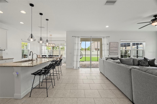 1844 Odiorne Point Ln, Wesley Chapel, FL 33543 - kitchen featuring a sink, light stone counters, open floor plan, recessed lighting, and white cabinets