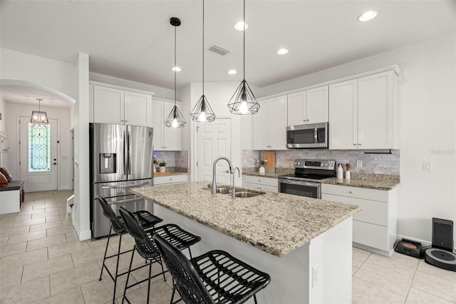 1844 Odiorne Point Ln, Wesley Chapel, FL 33543 - kitchen featuring stainless steel appliances, a sink, arched walkways, tasteful backsplash, and a breakfast bar