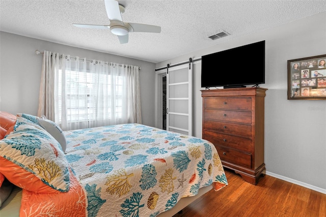 9209 Seminole Blvd Unit 156, Seminole, FL 33772 - bedroom with baseboards, a barn door, wood finished floors, a textured ceiling, and a ceiling fan