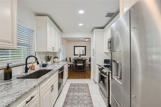 1145 53rd Ave N Unit 1, Saint Petersburg, FL 33703 - kitchen featuring appliances with stainless steel finishes, a sink, white cabinetry, recessed lighting, and light stone counters