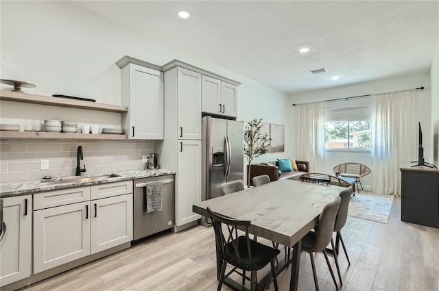 1145 53rd Ave N Unit 1, Saint Petersburg, FL 33703 - kitchen with stainless steel appliances, a sink, open shelves, light wood finished floors, and decorative backsplash