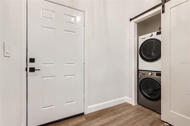 1145 53rd Ave N Unit 1, Saint Petersburg, FL 33703 - washroom with stacked washer / drying machine, a barn door, light wood-type flooring, and baseboards