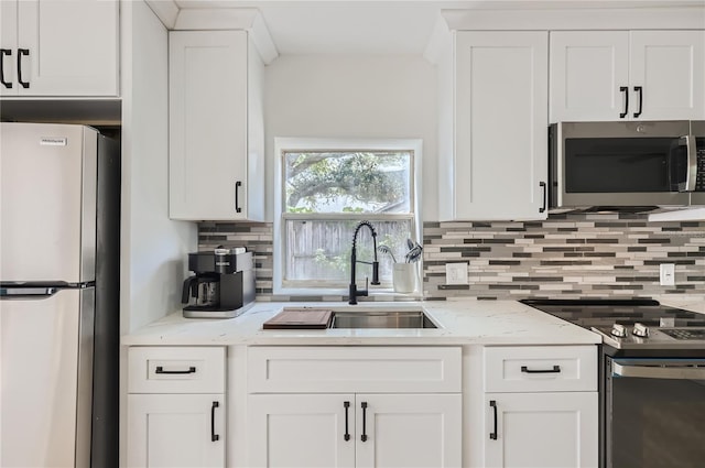 1145 53rd Ave N Unit 1, Saint Petersburg, FL 33703 - kitchen with stainless steel appliances, a sink, backsplash, white cabinetry, and light stone counters