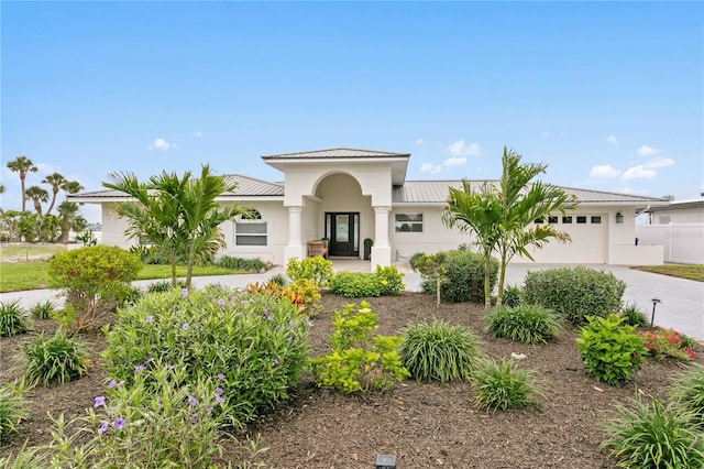 7060 S Shore Dr S, South Pasadena, FL 33707 - mediterranean / spanish-style home with concrete driveway, an attached garage, metal roof, stucco siding, and a standing seam roof