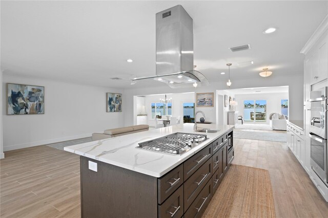 7060 S Shore Dr S, South Pasadena, FL 33707 - kitchen featuring open floor plan, a sink, appliances with stainless steel finishes, white cabinetry, and light wood-style flooring